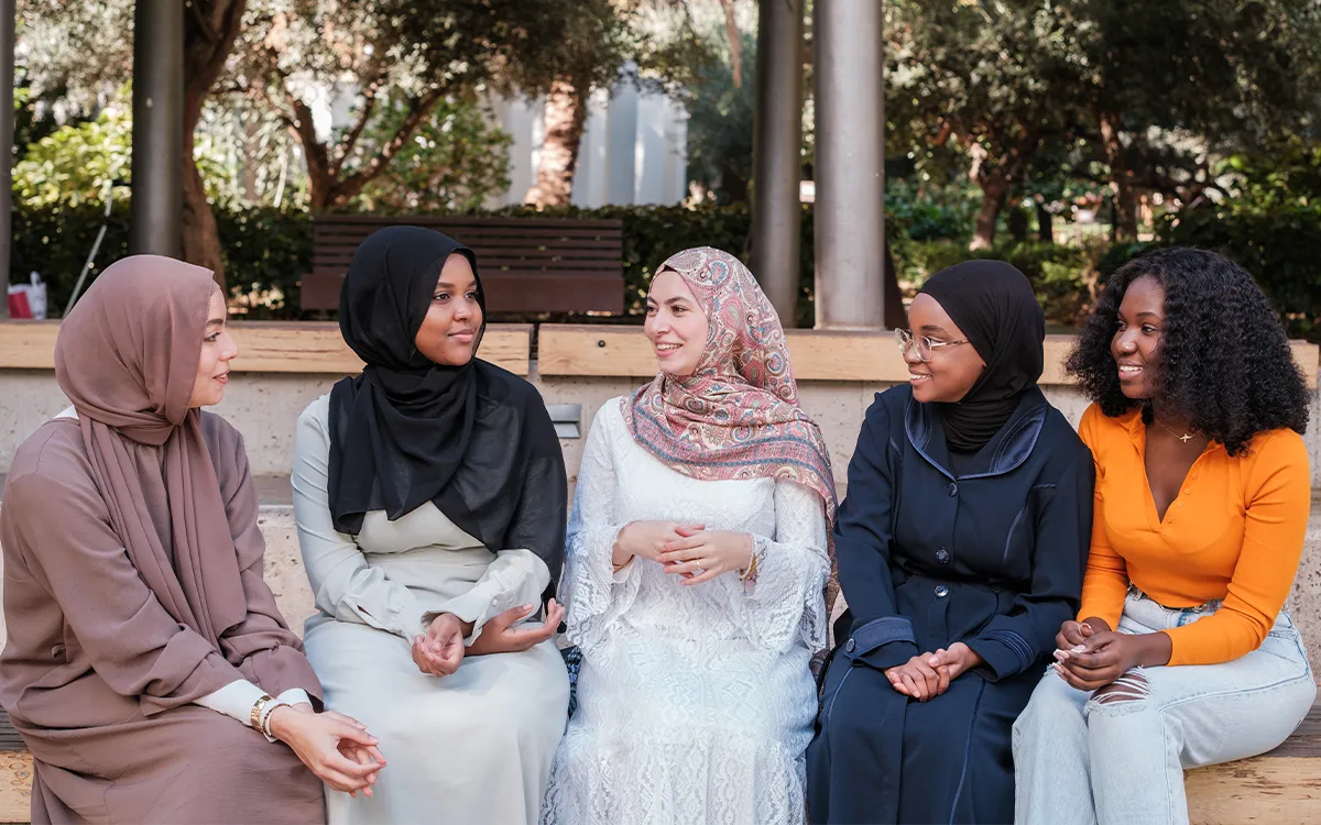 Groupe de femmes musulmanes échangeant et partageant un moment convivial en extérieur